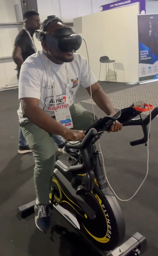 Visitor pedalling a stationary fitness bicycle while wearing a VR headset.