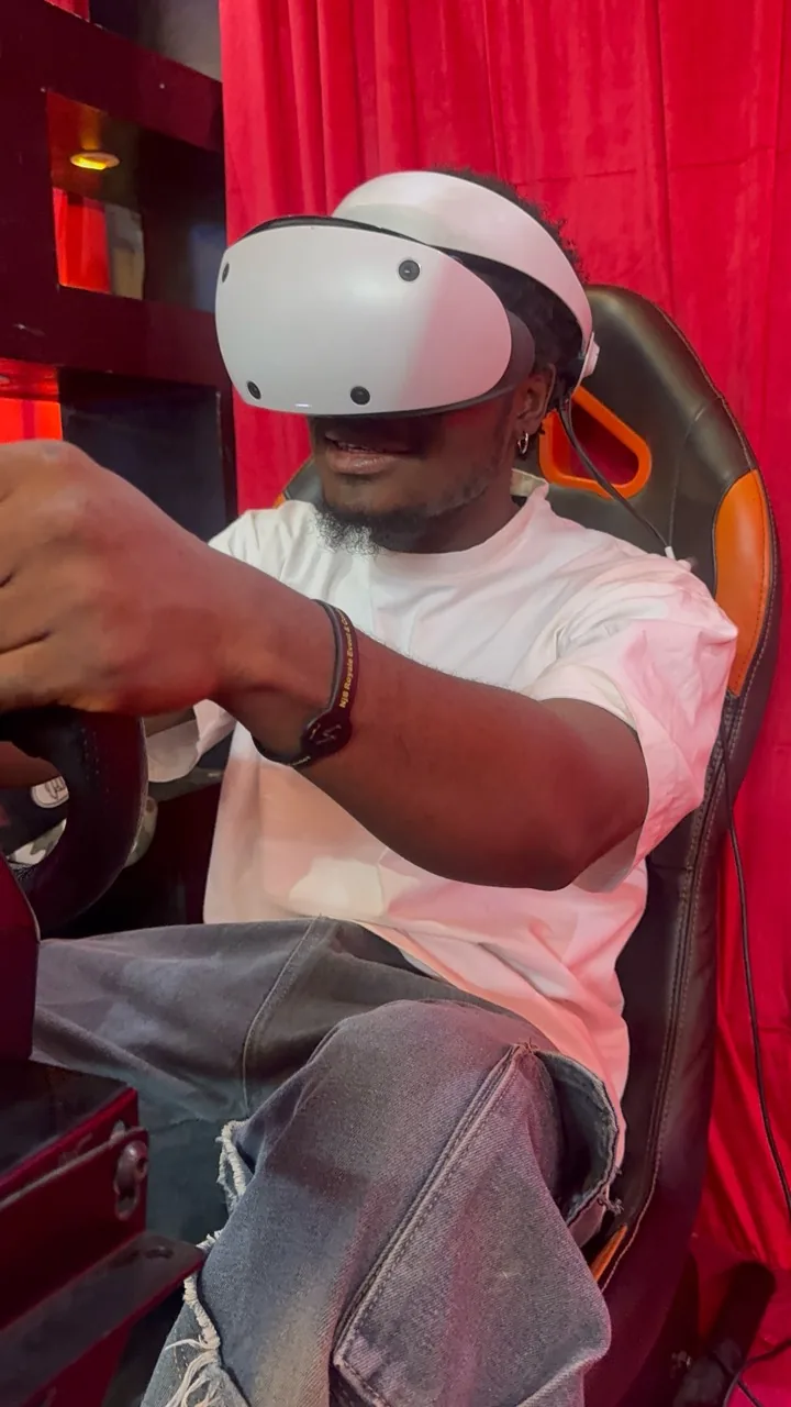 A real Player One guest smiling while taking on a VR racing challenge
