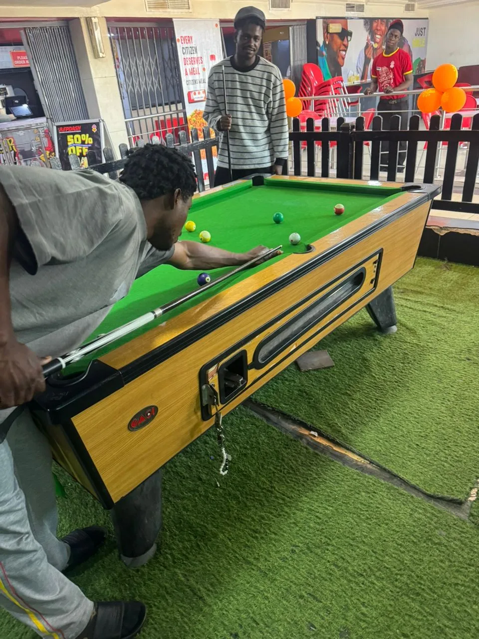 Snooker player taking a shot at Player One Game Cafe Yaba